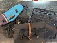 Photo showing four bags: blue and black Push the Envelope courier-style bag with 3-point harness, two basic black laptop bags, and one black canvas laptop bag with buckle.