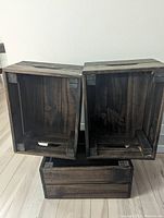 3 stackable wooden boxes shown from the front with two boxes resting on top of one box turned sideways to show inside and corner reinforcements.