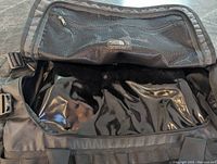 Close-up photo of inside of large black waterproof North Face duffel bag showing mesh zippered compartment and glossy base