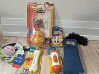 Photo of various new dog toys in packaging, including chew bones, treat toys, and plush toys