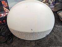 Front view of Hatch natural light and nature sounds alarm clock, white with gray fabric base, some minor marks visible