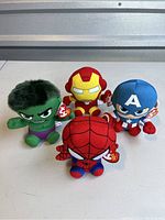 Photo showing four collectible Marvel Beanie Babies: Hulk, Iron Man, Captain America, and Spider-Man all seated on a table.