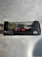 Side view of boxed Hot Wheels Elite Ferrari F2001 Michael Schumacher model car showing 2001 year decal and black packaging with clear plastic window.