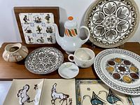 Full display of collection including multiple Mid-Century Modern ceramics and tiles on wooden surface