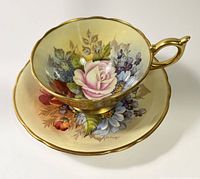 Aynsley Cabbage Rose teacup and saucer set, showing the floral design and gold trim, and signed Bailie on the saucer