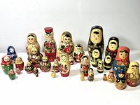 Full view of 28 vintage Matryoshka dolls arranged showing variety of styles, sizes, and colors including porcelain and pepper shaker types.