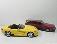 Yellow die-cast Dodge Viper and red plastic Volvo shown side by side on white surface.