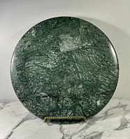 Full view of the large round green marble serving platter showing overall shape and surface pattern.