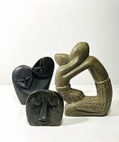 Three small stone sculptures displayed together on white background, showing scale and overall grouping.