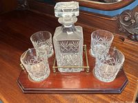 Decanter and four rock glasses set on wooden and brass tray from front angle, showing glass cut pattern details.
