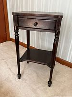 Front view of mahogany telephone table showing drawer, turned legs and lower shelf
