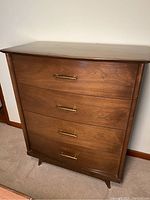 Front and angled front image of mid-century Krug highboy dresser showing warm brown wood finish, brass handles, and tapered legs
