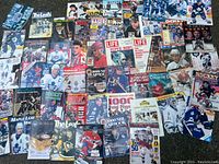 Wide view of the assortment of hockey magazines and books spread out showing various covers featuring players and teams.