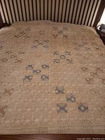 Hand crocheted lace coverlet spread on bed showing the detailed crochet pattern and scalloped edges.