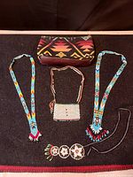 All four Native American beaded necklaces and the Pendleton clutch bag shown on dark fabric.