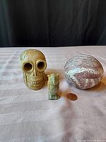 Natural stone hand carved skull, owl figurine, and a closed oval stone box with penny for scale