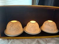 Set of three porcelain lithophane domed tealight holders displayed side by side, showing illuminated designs.