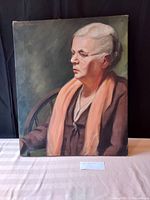 Frontal view of the oil portrait painting featuring an older woman wearing glasses and a scarf, set against a dark background.