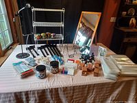 Photo showing entire assortment of items on table: folding shelving unit, bungee cords, plastic bags, wooden blocks, mirrors, labels, clothespins, clip-on lamp and iron holders.