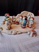 Full view of the Native American style Nativity set including various hand-painted figurines on a clay base, showing details like traditional clothing and beadwork.
