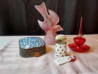 Group photo of the glass bird statue, porcelain shard box, porcelain trinket box, and red glass ring holder with penny for scale
