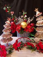 Full view of waffle cone Christmas trees, poinsettia garland, assorted sprigs in Rubbermaid container, and decorative holiday elements on table