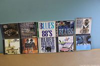 Shows all 10 Blues CDs arranged in two rows on a blue surface, clear view of the album covers.