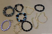 Overview photo displaying all 11 bracelets in a group, showing variety in style, size, and materials including chain link, glass beads, and natural stone beads.