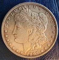 Obverse side of the 1897 Morgan silver dollar coin showing Lady Liberty's profile, date 1897, and 'E PLURIBUS UNUM' legend.