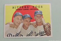 Front view of the 1959 Topps Hitters' Foes baseball card featuring Los Angeles Dodgers players Clem Laine, Don Drysdale, and Johnny Podres.