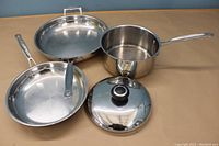 Photo of all three pans including 12-inch and 10-inch skillets and 8-inch saucepan with lid, arranged on a surface.