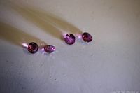 Four round cut pinkish purple Tourmaline loose gemstones arranged in a row on a white surface, showing their size range and color.