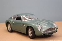 Close-up image of the 1/18 scale diecast model car showing its metallic green paint, detailed wire wheels, and body contours.