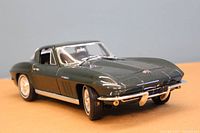 Front angle view of the dark green 1965 Chevrolet Corvette 1/18 scale model showing detailed front bumper, hood, headlights, and wheels.