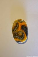 Top-down view of the oval picture agate cabochon showing detailed patterns and colors.