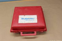 Closed red plastic Subaru emergency kit case with Subaru logo and 'Wait to Drive' text.
