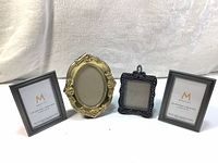 Four mini metal picture frames mix-matching in vintage and new styles, with easel backs, arranged side by side on fabric background.