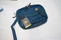 Front view of Gregory Graph 12 shoulder bag in blue with attached brand tag.