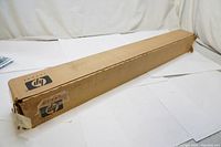 Sealed cardboard box with HP logo containing a roll of coated photo paper