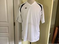 Front view of the Mizuno white athletic jersey on mannequin showing V-neck, black accents, and Mizuno logo on chest.