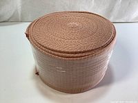 Image showing tightly rolled beige elasticated tubular bandage, viewed from the side