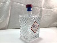 Front view of the Reid's Spiced Gin empty glass bottle showing the diamond-patterned texture and maroon cap.