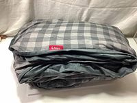 Photo of the Endy weighted blanket folded showing the grey checkered patterned side with Endy brand tag.