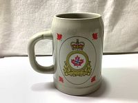 Full side view of the white ceramic beer stein mug with handle, displaying the Canadian Forces Europe emblem with red maple leaf motifs.