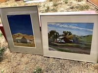 Overall view of two framed watercolor paintings leaning outdoors