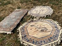 Three Oriental style rugs arranged on grass: two matching octagonal dragon rugs in cream and blue tones and one rectangular runner rug.