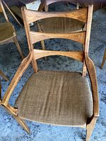 Front view of one armchair showing ladder-back design, armrests and brown fabric seat