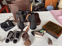 Overall overview photo of the lot contents including binoculars, cases, bird figurines, and decorative box.