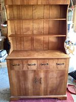 Front view of wooden farmhouse hutch showing upper shelves, drawers, and lower two-door cabinet