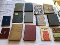 Full overview of 15 vintage books laid out on table, assorted poetry, plays, cooking, botany, and Spanish reader books from early to mid-20th century.